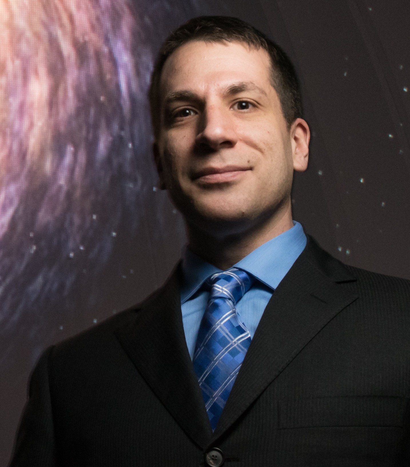 Headshot of Kayhan Gultekin, looking very handsome and professional despite the fact that he is not wearing a labcoat, only a fantastic suit.