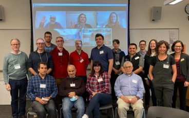 Group picture of 16 scientists in person with 3 virtually projected behind them.